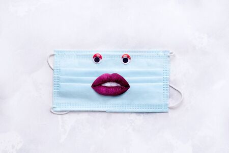 creative collage with a medical mask and a sad face.の写真素材