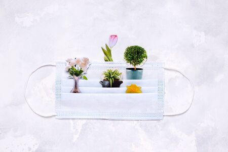 collage with a medical mask and flowers on a white background. concept of spring and summer during the virusの写真素材