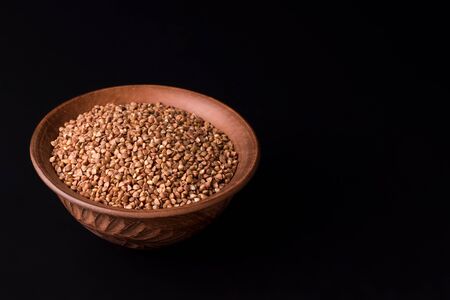 buckwheat in a clay bowl on a black background. copy spaceの写真素材