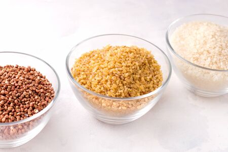 Dry cereal bulgur buckwheat and rice on a white backgroundの写真素材