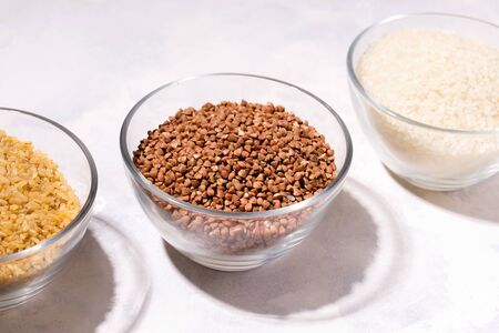 raw buckwheat porridge, bulgur, rice in a glass bowl on a white backgroundの写真素材