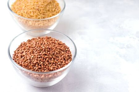 Buckwheat groats in a glass bowl on concrete background. Copy space.の写真素材
