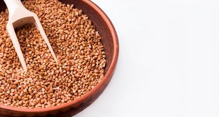 Buckwheat in a clay bowl close-up on a white background. Copy space. Bannerの写真素材