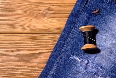 jeans with threads on a wooden background. copy space. sewing concept restoration of old thingsの写真素材