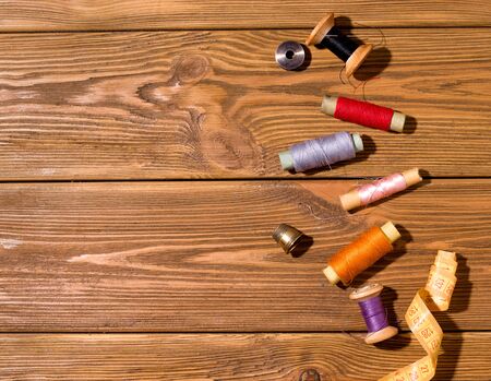 Threads of different colors on a wooden table. Copy space. The concept of sewing and repairing old thingsの写真素材