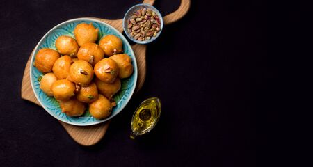 Lokma is a sweet dish in Greek, Turkish, Persian and Arabic cuisines. Dessert of sweet fried balls in a plate on a black backgroundの写真素材