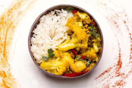 Aloo gobi traditional Indian dish of vegetables and spices in a bowl on a wooden boardの写真素材
