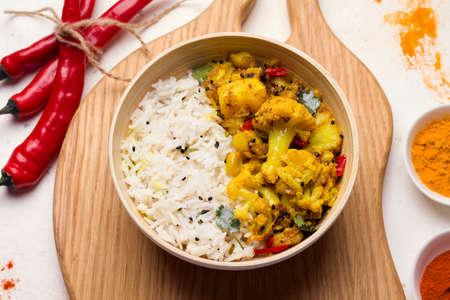 Aloo gobi traditional Indian dish of vegetables and spices in a bowl on a wooden boardの写真素材