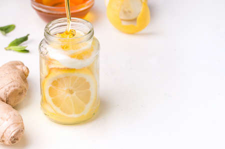 Healthy food. Lemon in a jar with honey and ginger on a white background. Copy spaceの写真素材