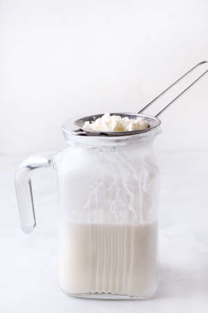 Fermented milk drink kefir with granules of bacteria on a white background. Copy space. Vertical photoの写真素材