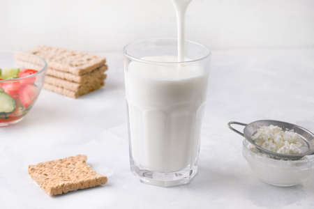 Fermented kefir yogurt is poured into a glass on a white background. Healthy breakfast conceptの写真素材