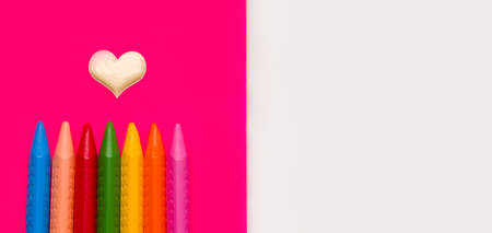 Crayons for drawing different colors on a pink notebook. Copy space.の写真素材