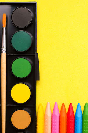 Crayons and paints on yellow paper. Copy space. The concept of children's creativity and drawing lessons.の写真素材
