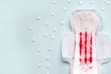 PMS pain treatment concept. pad on blue background next to pills.copy spaceの写真素材