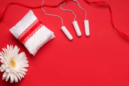 The concept of protection during menstruation. Gaskets and tampons on a red background. Copy spaceの写真素材