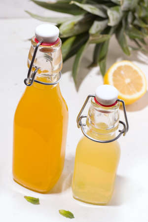 Pineapple and lemon summer drinks in glass bottles on a white backgroundの写真素材