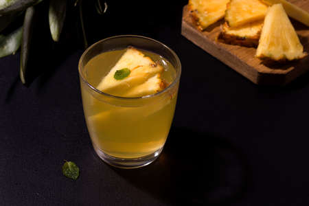 Tropical summer pineapple drink on a black background, next to the ingredients. Copy spaceの写真素材