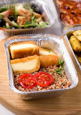 Healthy food delivery. Buckwheat porridge in a container with vegetables and micro greens and cheese on a white backgroundの写真素材