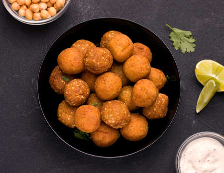 A Middle Eastern vegan dish, falafel. Fried ready-made balls in a bowl on a black background. View from aboveの写真素材