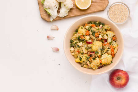Summer salad with cauliflower, quinoa, apple in lemon sauce with parsley on a white plate. Copy spaceの写真素材