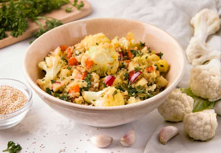 Salad with cauliflower and quinoa on a white plate next to the ingredientsの写真素材
