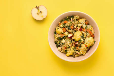 Summer salad with cauliflower, quinoa, apple and parsley on a yellow background. Copy spaceの写真素材