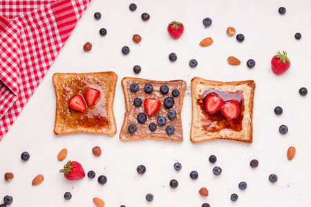 peanut butter and jelly sandwich on a white plate next to fresh berriesの写真素材