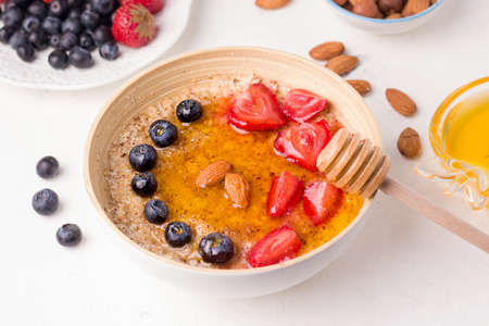 Healthy vegetarian breakfast with porridge and berries topped with honeyの写真素材