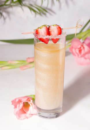 Shimmer drink garnished with strawberries next to flowersの写真素材