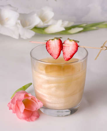 Gold-colored shimmer cocktail next to flowersの写真素材