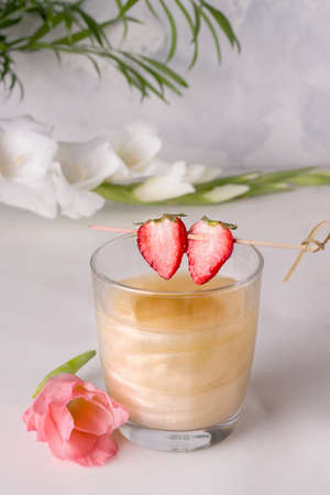 A drink with a shiny shimmer next to flowersの写真素材