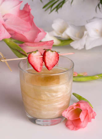 Golden shimmer drink next to flowersの写真素材