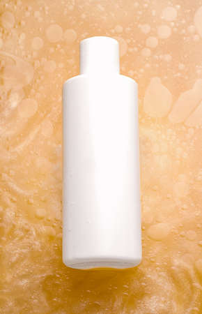Mockup of cosmetics and hygiene products. White bottle in water with orange shimmerの写真素材