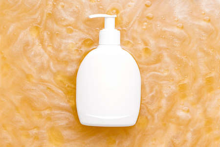 Mockup of a cosmetic product in a white bottle with a dispenser in water with a shimmer. View from aboveの写真素材