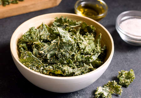 Kale chips in a bowl on a black tableの写真素材