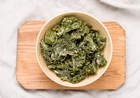 Kale chips in bowl on wooden board top viewの写真素材