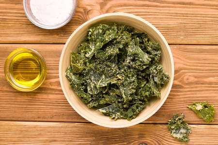 Kale chips on wooden background close-up, top viewの写真素材