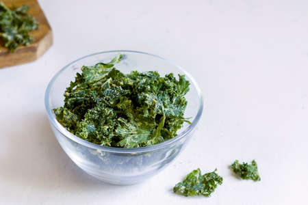 Kale chips in a glass bowl on a white background. copy spaceの写真素材