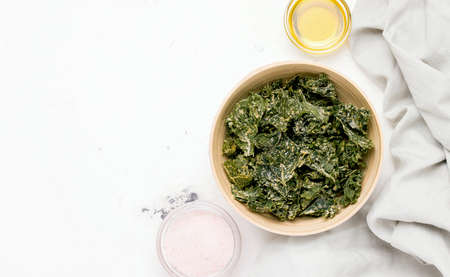 Kale chips in a bowl on a white table. View from above. Copy spaceの写真素材