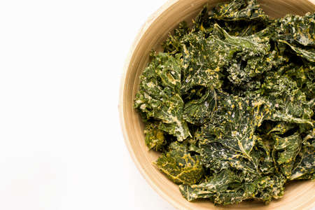 Kale chips close-up in a bowl on a white background.の写真素材