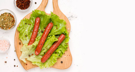 Vegetarian spiced sausages on lettuce leaves. White background. Copy space. Bannerの写真素材