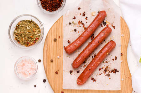 Vegetarian sausages with spices and tomato on a wooden plank next to the spicesの写真素材