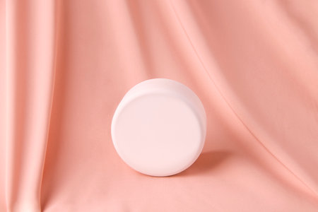 Mockup cosmetics. Round, white jar on a pink silk backgroundの写真素材