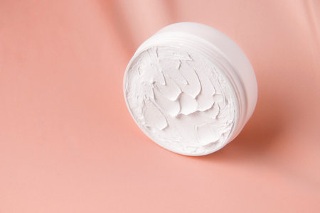 Cream in a white jar on a pink background. copy spaceの写真素材