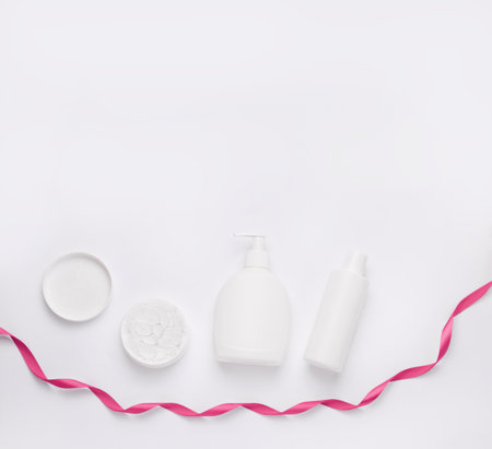 Mockup of a gift set of cosmetics. Copy space. White vials on a white background with a red ribbon. Minimalismの写真素材