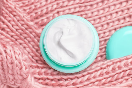 Jar of mint cream close-up on the texture of a pink scarf.の写真素材