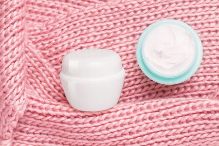 Winter skin care cream. Two jars of cream in a knitted pink scarfの写真素材