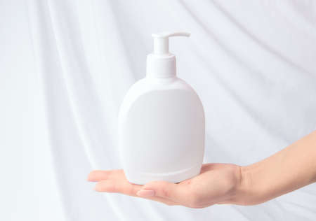 Mock up liquid gel soap. Female hand holding bottle with dispenser on white backgroundの写真素材