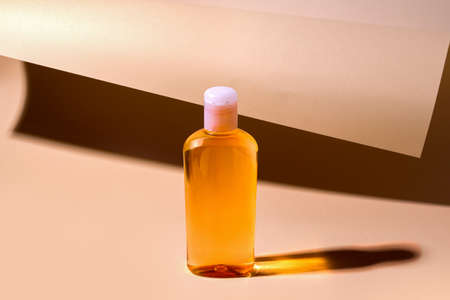 Orange cosmetic shampoo, gel on beige rolled paper backgroundの写真素材