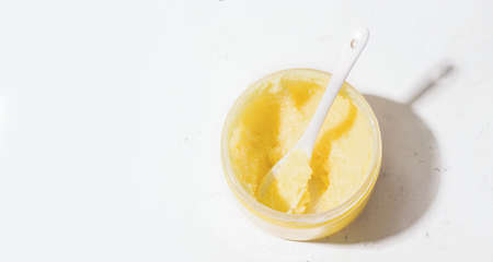 Scrub yellow in a jar on a white background. Copy space. View from above